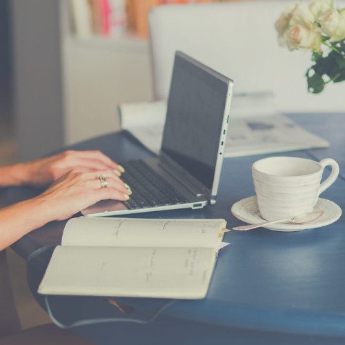 Woman working on her laptop next to a coffee mug