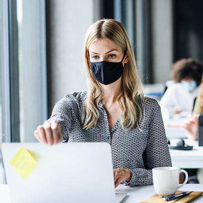 Woman wearing a mask working on her laptop